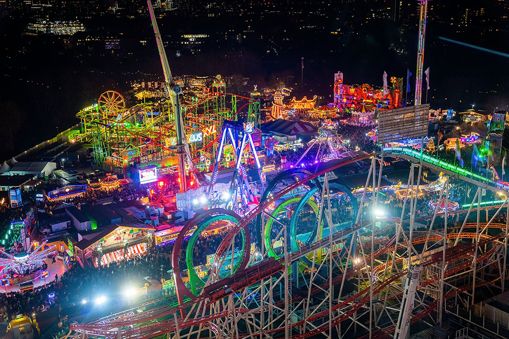 A sweeping bird's-eye view showcases a winter wonderland, with the colourful rides and winter market