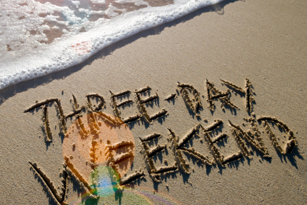 '3-day Weekend' inscribed on a sandy beach, with the foamy edge of an incoming wave about to wash over the letters.