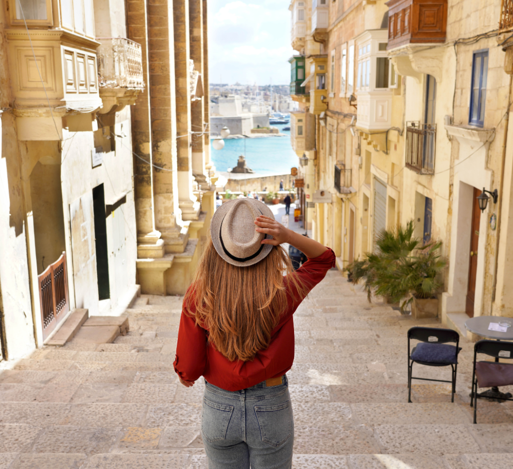 Back view of traveler woman descends stairs in the historic city of Valletta, UNESCO World Heritage, Malta.