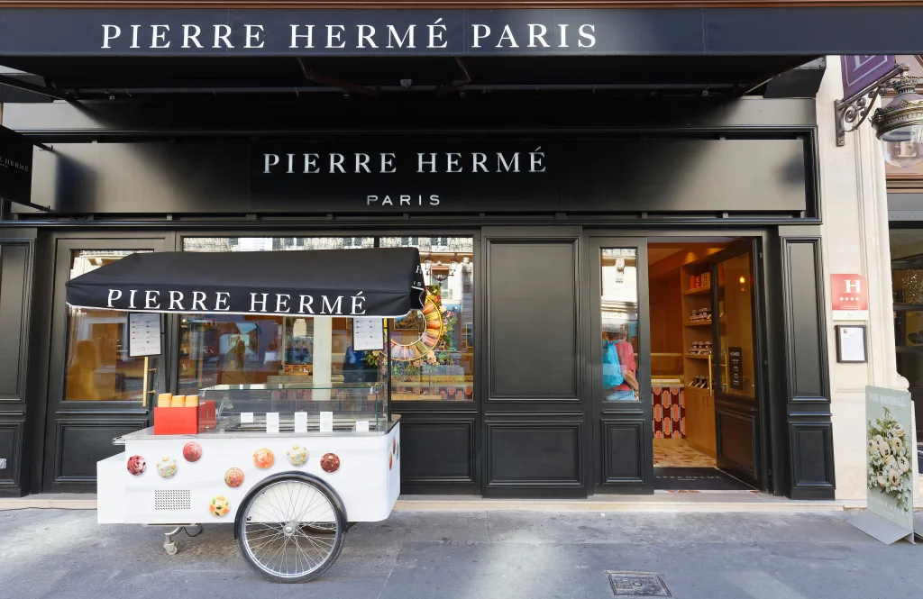 Storefront of the Pierre Herme Paris Paisserie, with a trolley in front